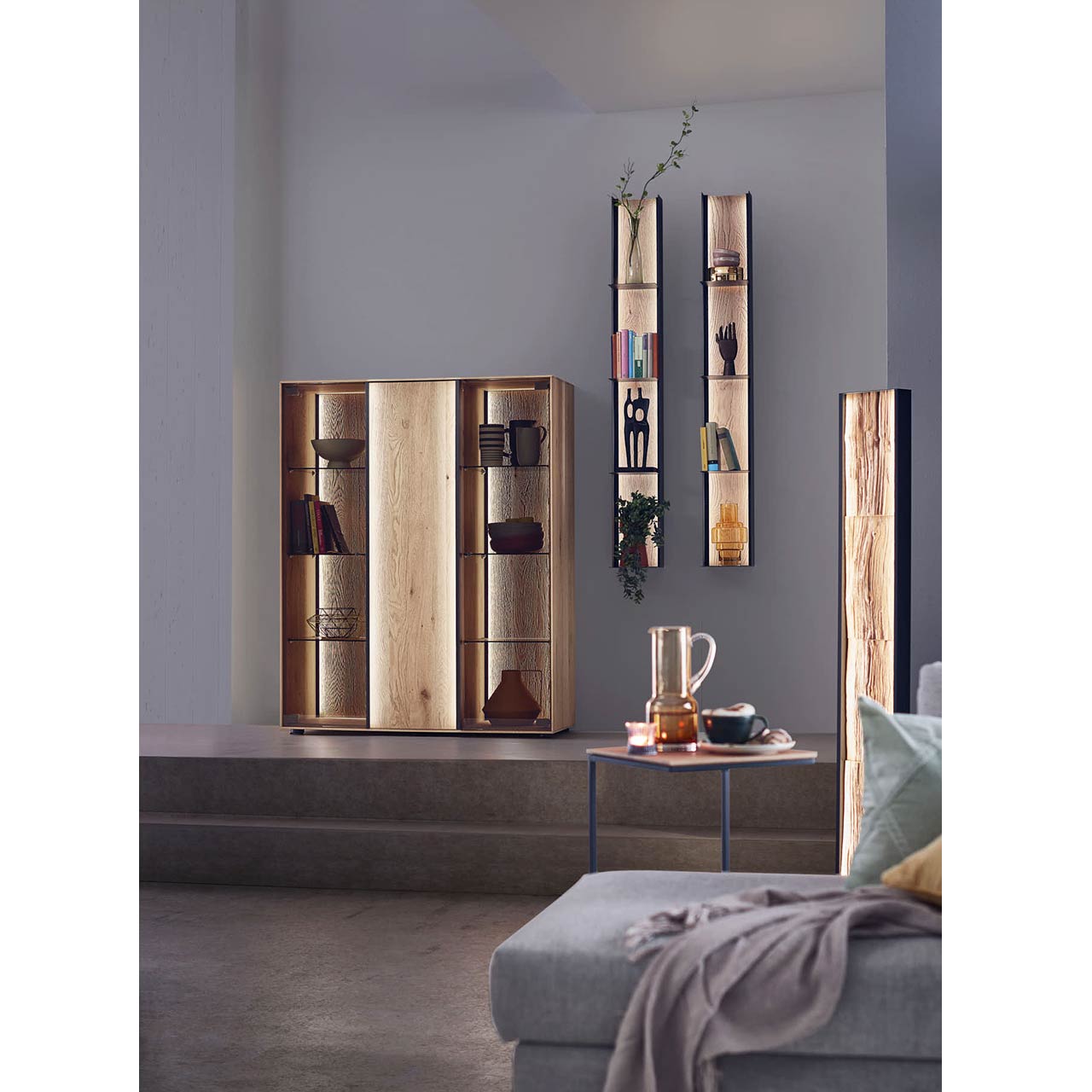 Modernes Highboard aus Kerneiche, sandgestrahlt, mit 2 Glastüren & dekorativem Riffholz mit weiteren Hängelemeneten vor einer grauen Wand