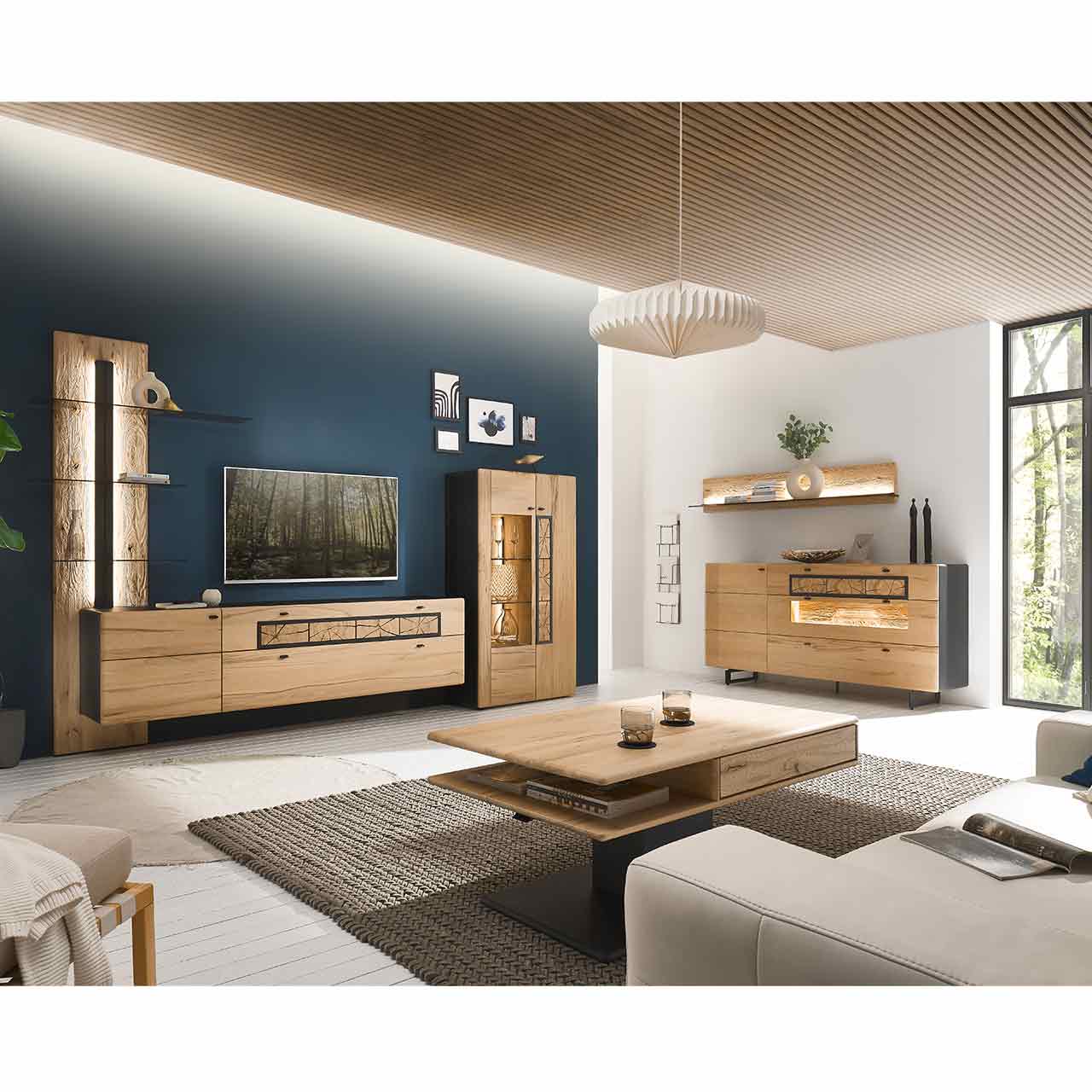 Wohnzimmer mit Wohnwand aus Kernbuche: links Wandpaneel mit Glasböden, Hängelowboard und Highboard mit Holz-/Glastür. Rechts Sideboard auf Metallkufen mit Hirnholzscheiben und Glasfront, darüber ein Paneel
