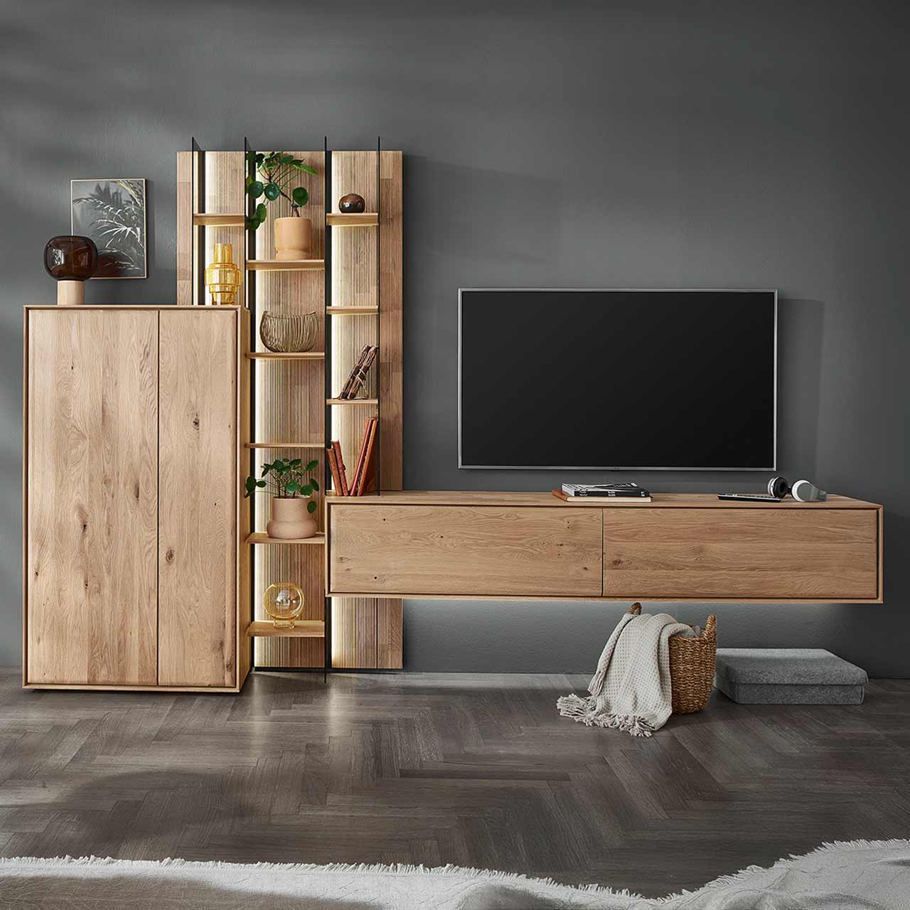Moderne dreiteilige Wohnwand aus massiver Kerneiche Natur bestehend aus einem Highboard mit zwei Holztüren, einem hohen Wandregal mit Holzböden, beleuchteten Glasseiten und geschroppter Rückwand und einem darin integriertem Hängelowboard.