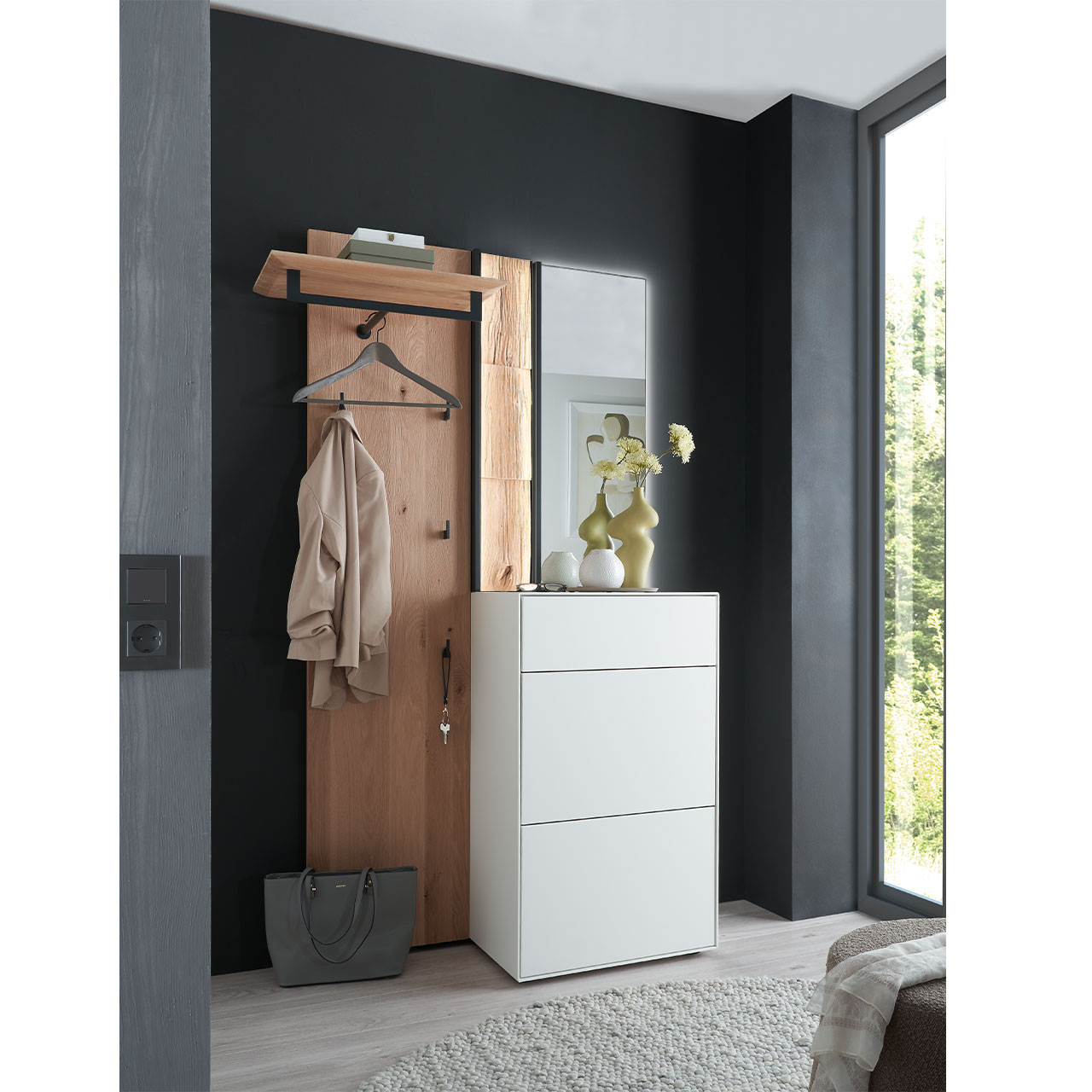Flur mit modernen Garderobenmöbeln aus Kernbirke und Kerneiche Natur: Wandpaneel aus Holz mit Kleiderstange, Haken und Spaltholz-Akzent, ein Stauraumschrank mit Schubkasten und Klappen in Lack weiß, ein rechteckiger Spiegel.