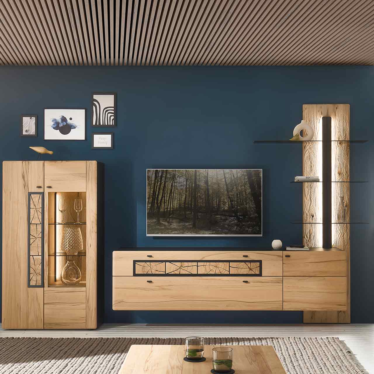 Wohnzimmer mit Wohnwand aus Kernbuche: Wandpaneel mit Glasböden, Hängelowboard mit Holztür und Schubkästen. Daneben Highboard mit Glas- und Holztür, verziert mit Hirnholzscheiben.