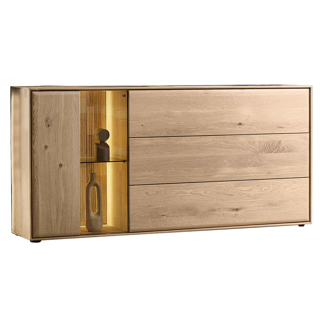 Hartmann VALA - Sideboard 8640-4183 - Kerneiche Natur / Glas Modernes Sideboard aus massiver Kerneiche Natur mit einer beleuchteten Glas/Holztür links und einer Holzklappe und zwei Holzschubkästen rechts - in Seitenansicht.