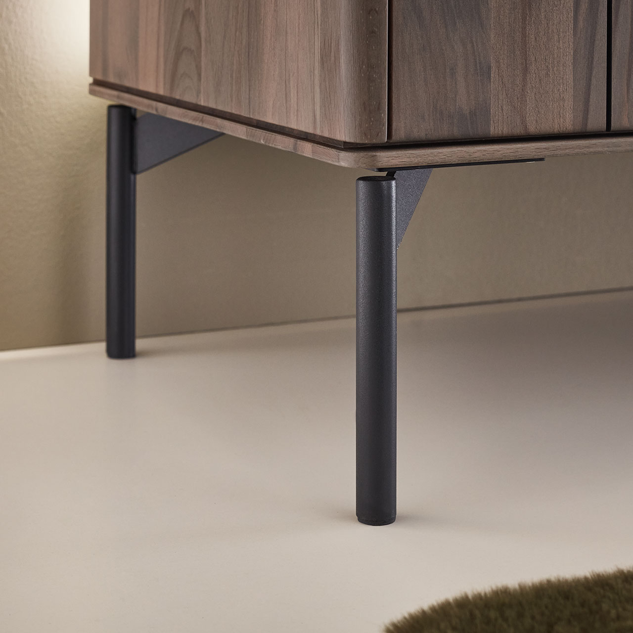 Detailansicht der schwarzen Metall-Füße, die an einem Sideboard aus dunkelbraunem Holz angebracht sind.