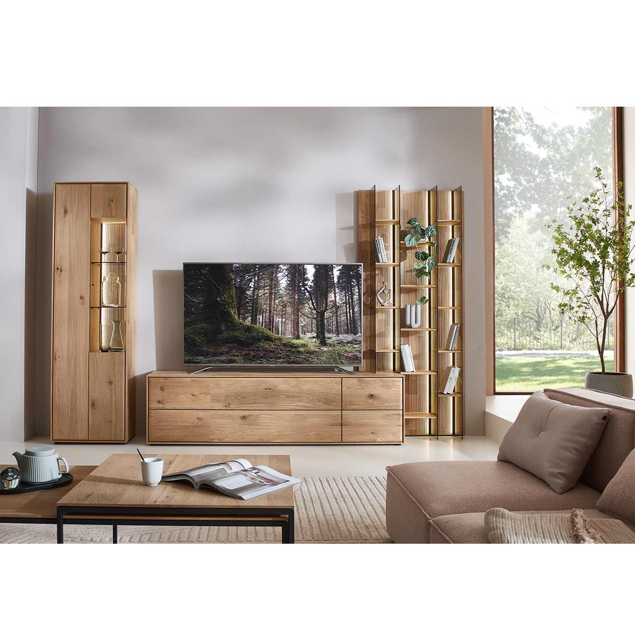 Modernes Wohnzimmer mit dreiteiliger Massivholzwohnwand bestehend aus einer Standvitrine,  einem hohen Wandregal mit Holzböden, beleuchteten Glasseiten und geschroppter Rückwand und einem darin integriertem Lowboard. Davor passender Couchtisch