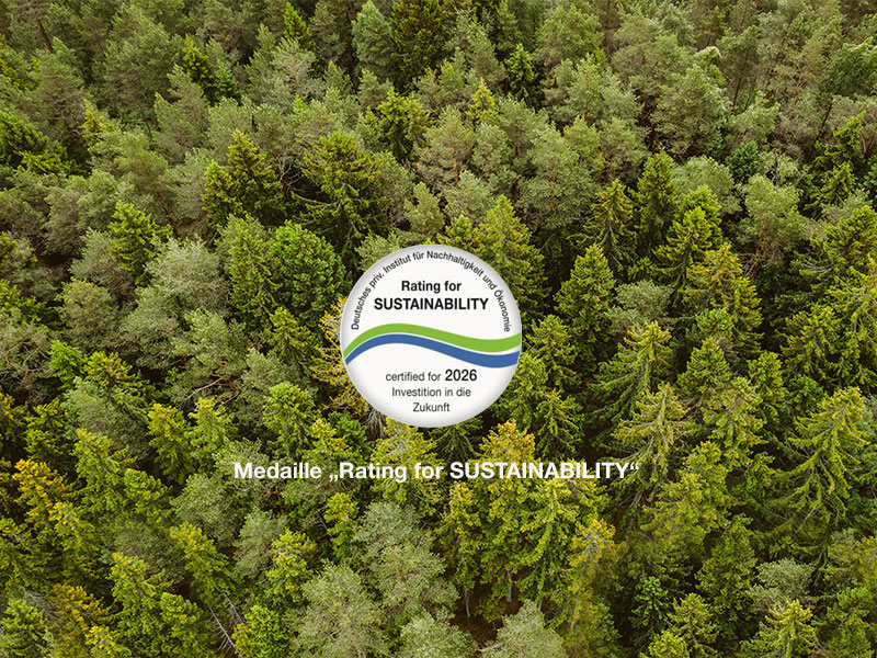 Hartmann Möbel - Kategorie Service - Teaser Siegel RatingForSustainability Teaser mit dichtem, grünen Wald als Ansicht von oben und offiziellem Rating Siegel „RatingForSustainability“. Unter dem Siegel Text in weißer Schrift: Medaille RatingForSustainability