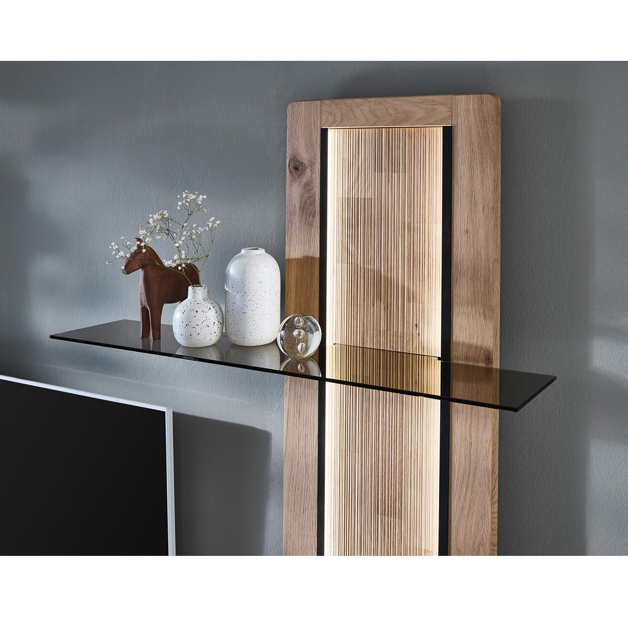 Detailbild - Hartmann VIDA - Aufsatzpaneel rechts 8630-0102 - Kerneiche Natur Detailansicht des VIDA Wandpaneels mit Beleuchtung der geschroppten Rückwand sowie des oberen Glasbodens aus edlem Parsolglas.