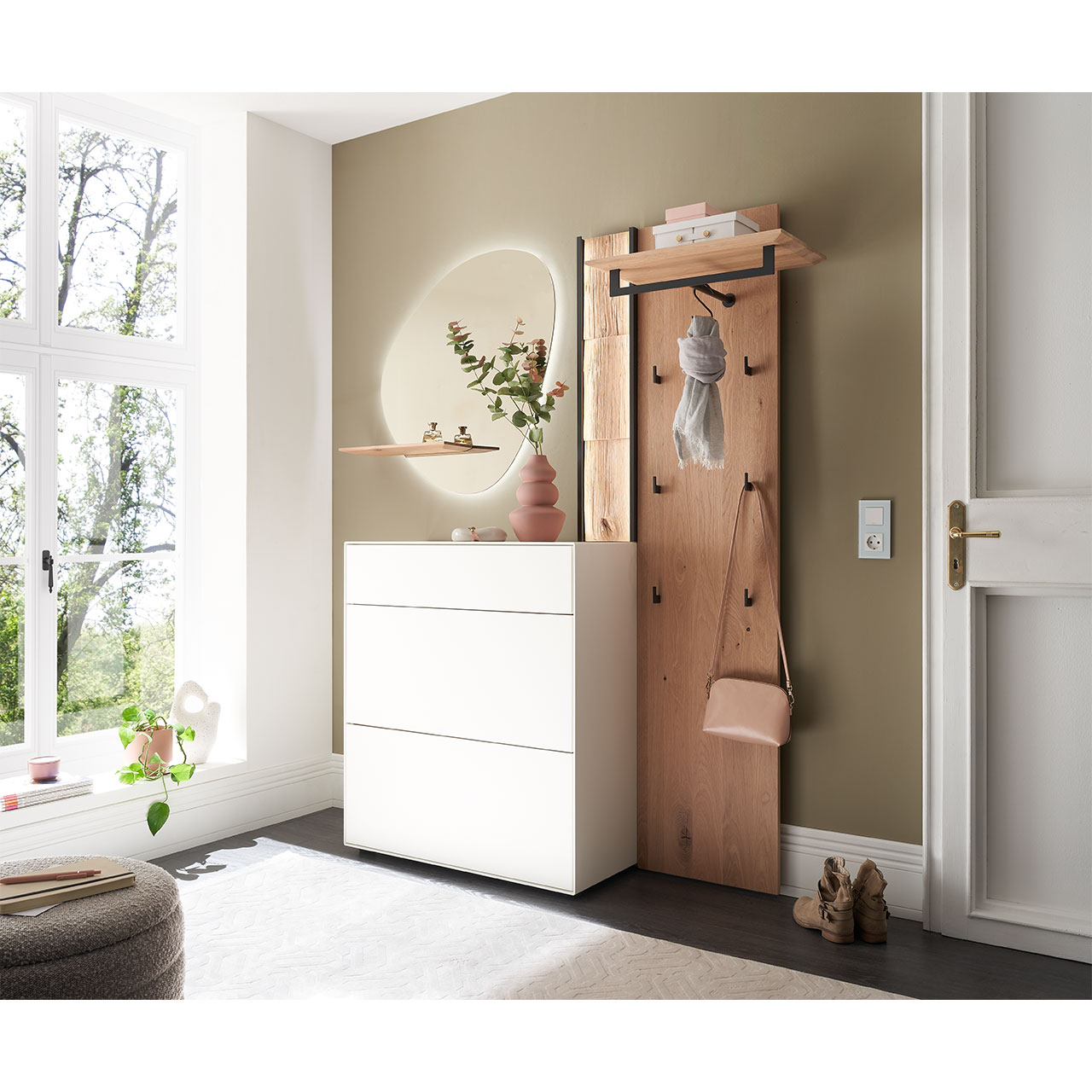 Flur mit modernen Garderobenmöbeln aus Kernbirke und Kerneiche Natur: Wandpaneel aus Holz mit Kleiderstange, Haken und Spaltholz-Akzent. Ein Stauraumschrank mit Schubkasten und Klappen in Lack weiß, ein ovaler Spiegel mit Ablage.