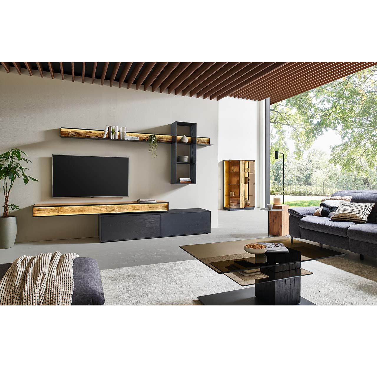 Moderne Wohnwand mit Materialmix aus Lack anthrazit mit Spaltholz-Akzenten und Parsolglas-Vitrinenausschnitten