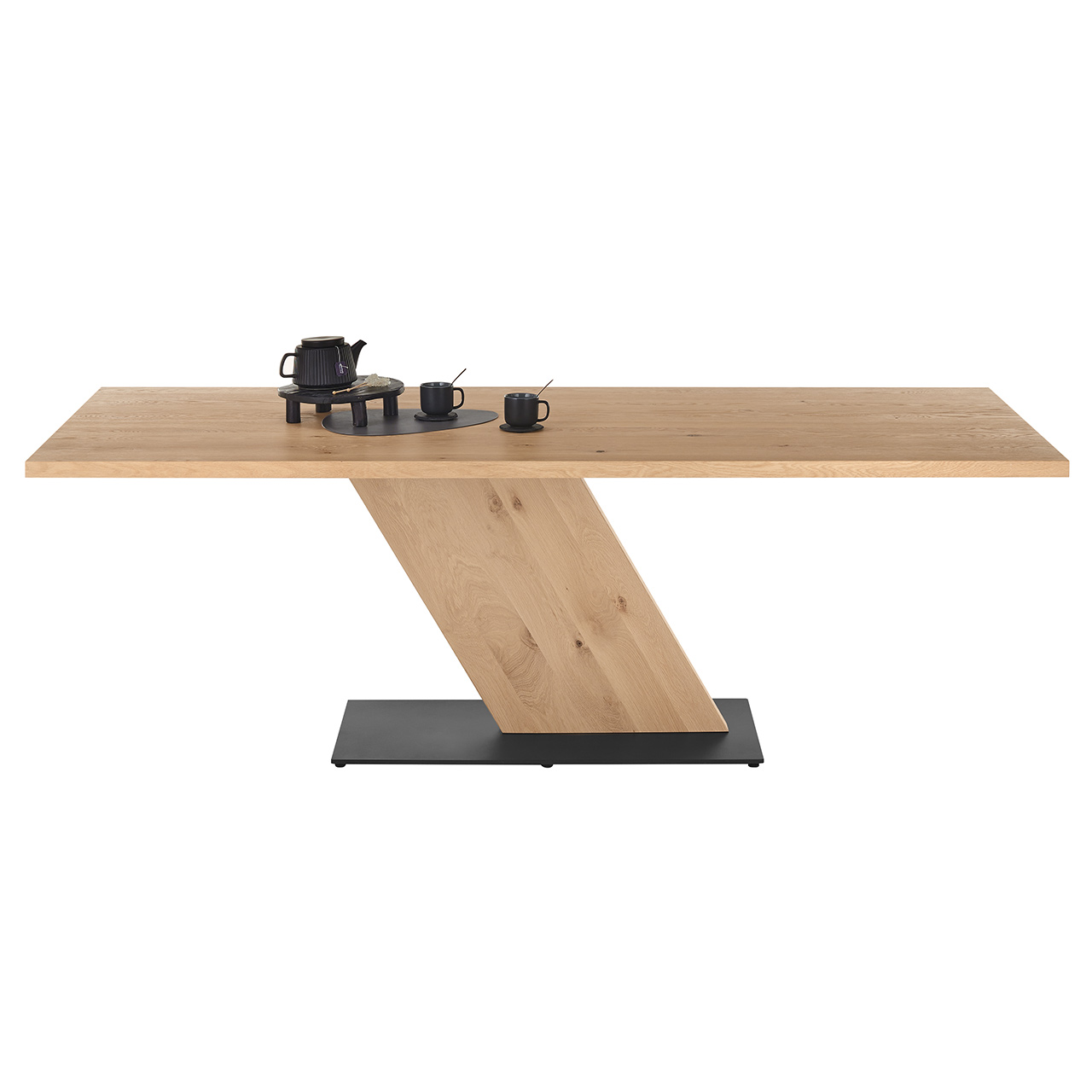 Moderner Esstisch aus heller, massiver Kerneiche mit fester, rechteckiger Tischplatte und markantem, schräg gestelltem Mittelfuß-Element aus Massivholz. Unten stabile Bodenplatte aus massivem Holz, anthrazit lackiert - in Frontansicht.