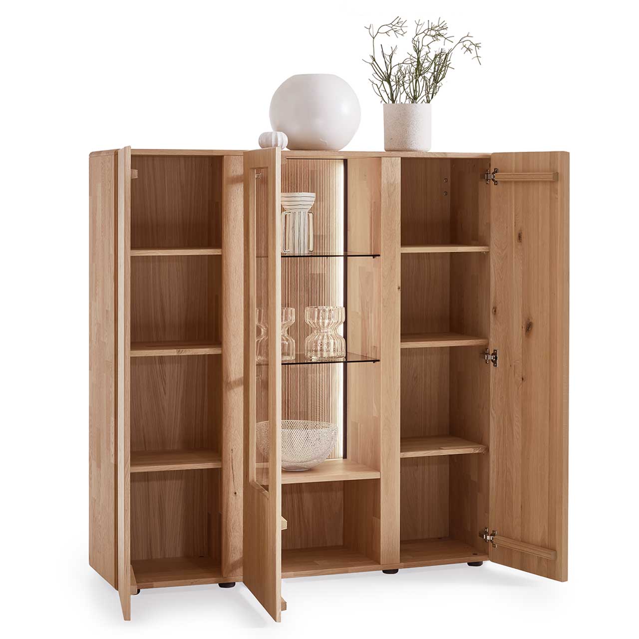 Hartmann VIDA - Highboard 8630-7141 - Kerneiche Natur / Glas - offen Modernes 3-türiges Highboard aus massiver Kerneiche Natur mit zwei offenen Holztüren rechts und links und den dazugehörigen sechs Holzeinlegeböden, sowie mittig mit einer geöffneten Glas-/Holztür, mit zwei Glaseinlegeböden und einem Holzboden.