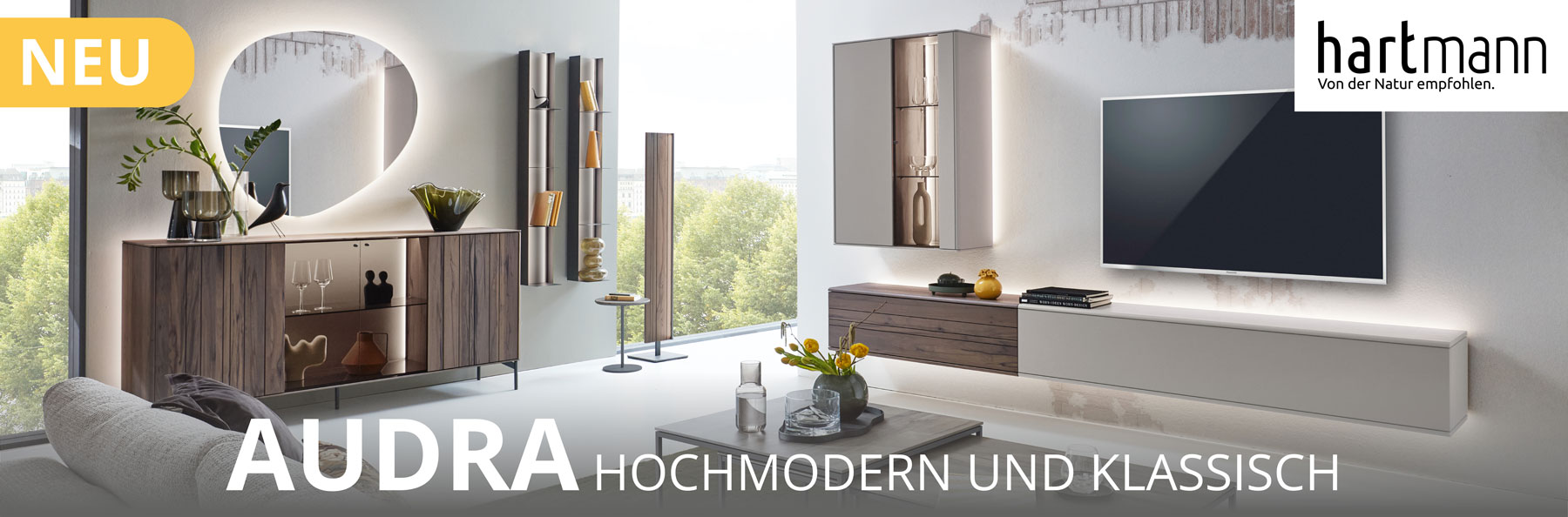 Hartmann TORIDO - Moderne Möbel aus massiver Altholzbuche Uyaa kombiniert mit sandfarbenen Lackfronten. Ambientebild zeigt Wohnzimmer mit dreiteiliger Wohnwand, Couchtisch, zwei Hängeregale und Sideboard mit Metallfüßen darüber moderner Spiegel.