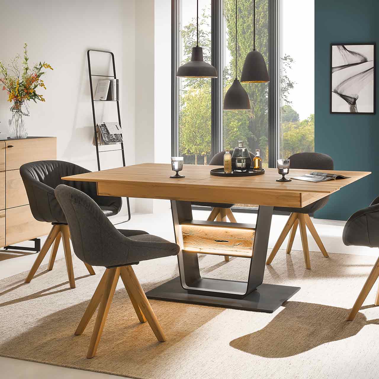 Elegant eingerichtetes Speisezimmer mit gedecktem Esstisch und vier Stühlen. Der Esstisch ist aus massiver Kernbuche mit Holzgestell anthrazit in moderner U-Form. Darin dekorativ eingebettet ist eine beleuchtete Holztraverse in edler Riffbuche.