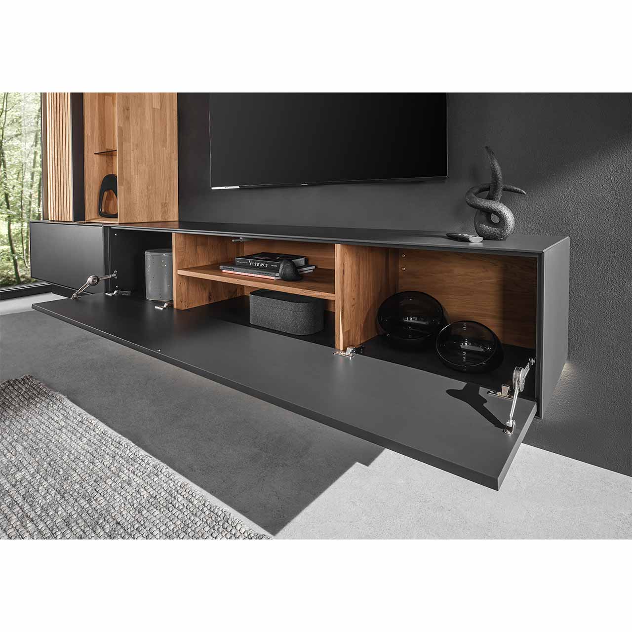 Detailaufnahme eines schlichten Hängelowboards aus massiver Birke in Anthrazit mit geöffneter Klappe. Innenleben aus hellem Holz unterteilt in vier Fächer.