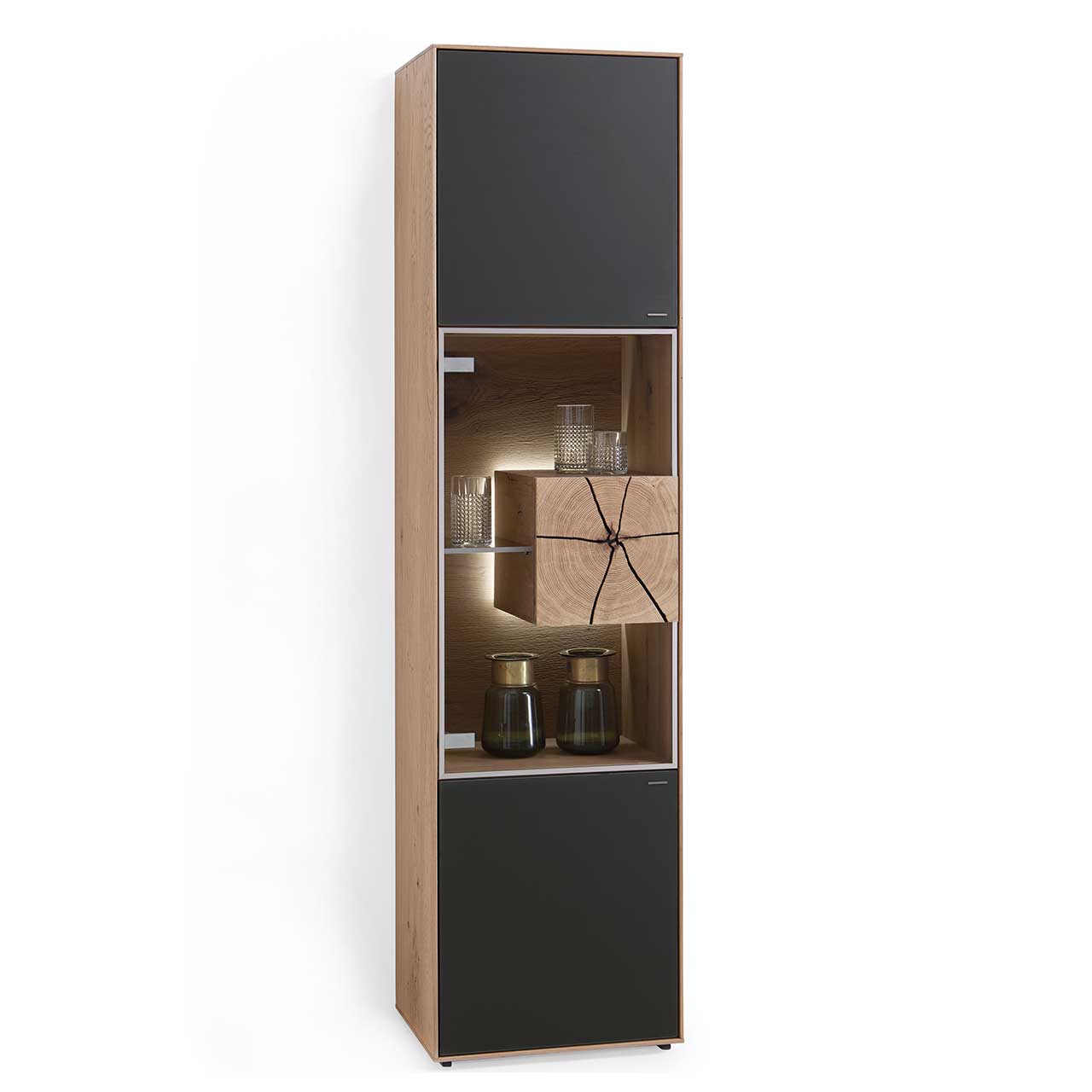Hartmann CAYA - Standvitrine 7170-0051A - Türanschlag links Moderne Standvitrine aus massiver Kerneiche Umato mit Mattglas anthrazit Front, mittig mit beleuchtetem Glasausschnitt, Glasboden und Hirnholzblock aus hellem Holz.
