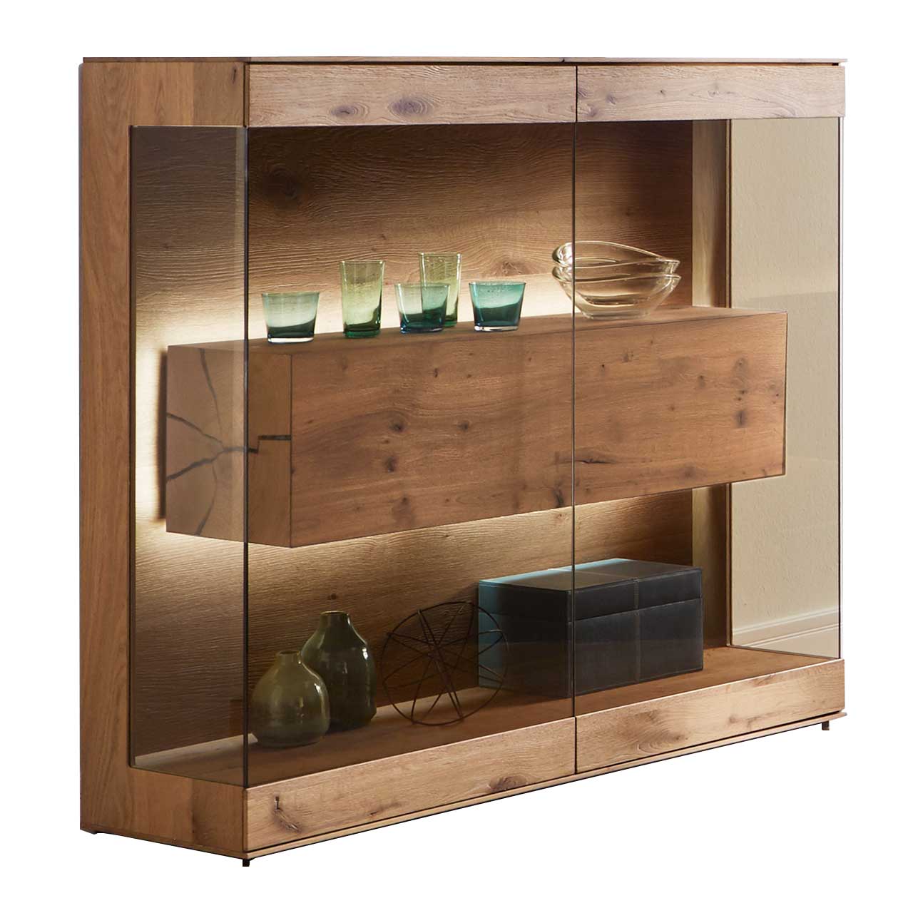 Hartmann CAYA - Highboard mit Glasfront 7170-HM-6139 Edles Highboard aus massiver Kerneiche Umato mit großen über Ecke verlaufenden Glastüren in Parsolbronze. Innenliegend ein großer, beleuchteter Hirnholzblock mit Doppelschubkasten.