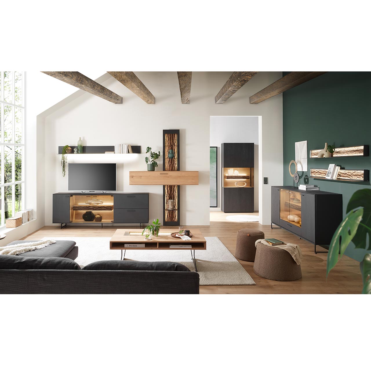 Milieubild Hartmann RUNA 8410 - Wohnmöbel aus massiver Kerneiche Natur Anthrazit gebeizt Modernes Wohnzimmer mit Wohnwand, Sideboard, Vitrine und Wandregalen aus massiver Kerneiche Natur anthrazit gebeizt, teils mit beleuchteten Glasausschnitten und Rinden-Akzenten. Im Vordergrund ein passender Couchtisch.
