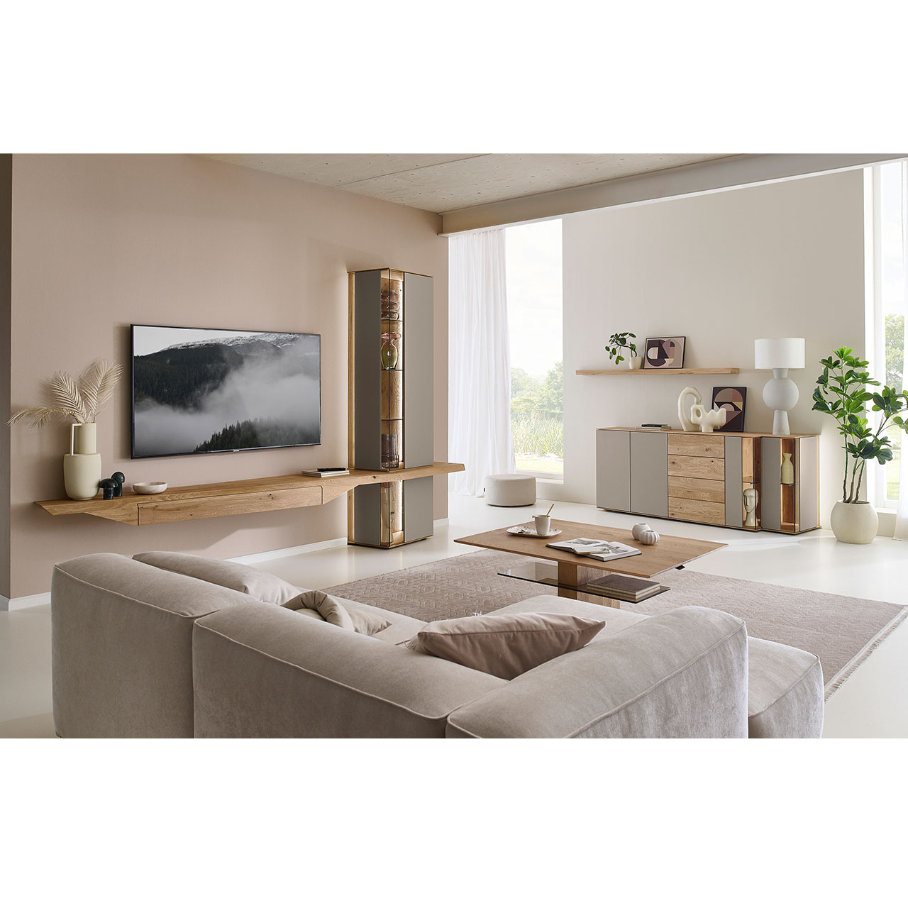 Hartmann Möbel SVEA - Wohnkombination 8660 Nr. V22 SV - dreiteilig aus Kerneiche Natur, Lack Sand - Milieubild Wohnzimmer mit Massivholzwohnwand aus Kerneiche mit Lack Sand und Riffholz bestehend aus Hängelowboard mit Schubkasten, Hängevitrine sowie Unterbauvitrine - im asymmetrischen Design. Rechts passendes Sideboard mit Glastüren, davor Holz-Couchtisch.