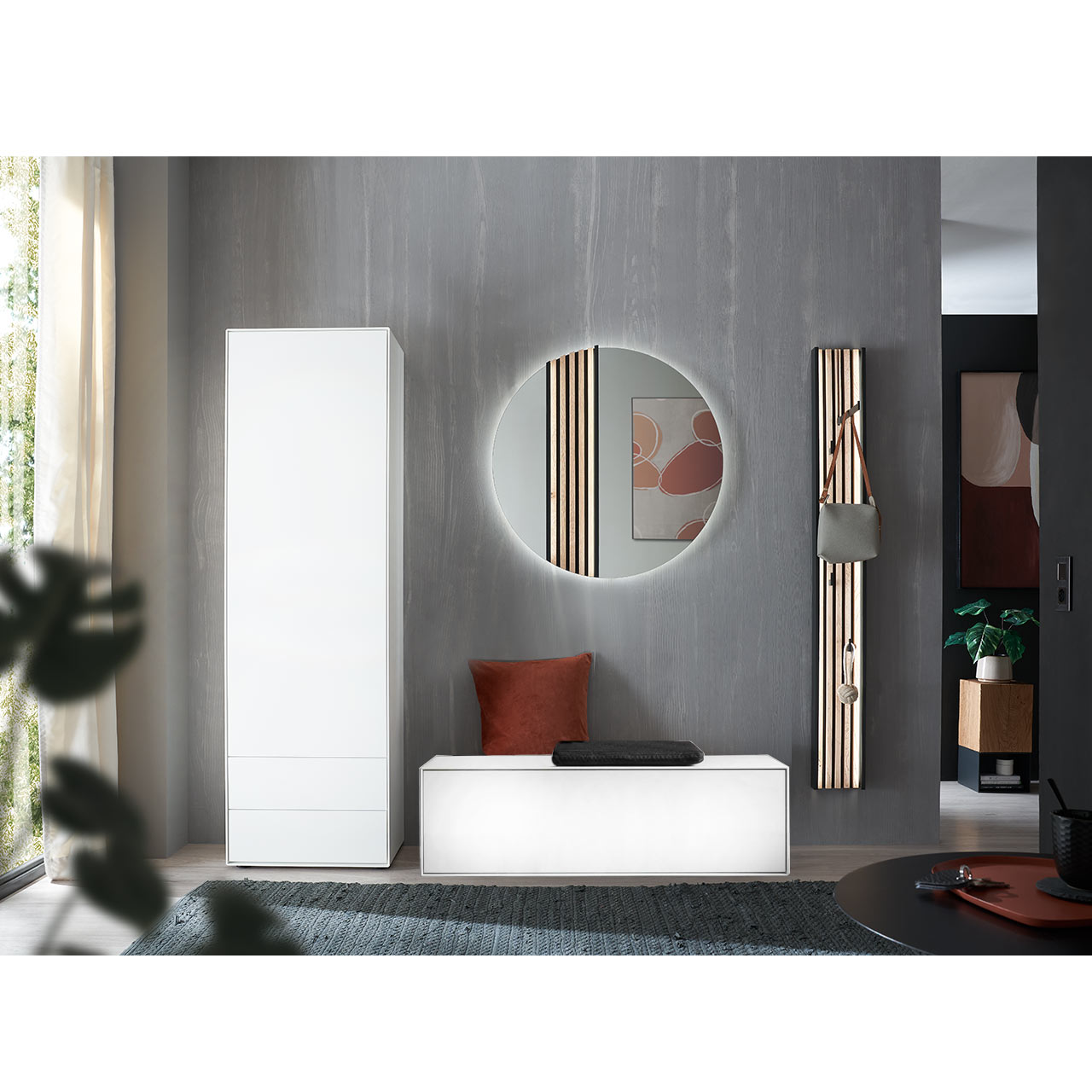 Flur mit modernen Garderobenmöbeln aus massivem Holz in Lack weiß: Schmaler Hochschrank, Sitzbank mit Stauraumfach, runder Wandspiegel mit Lamellen-Akzent und Wandgarderobe mit Kleiderstange, Metallhaken und Lamellen-Rückwand.