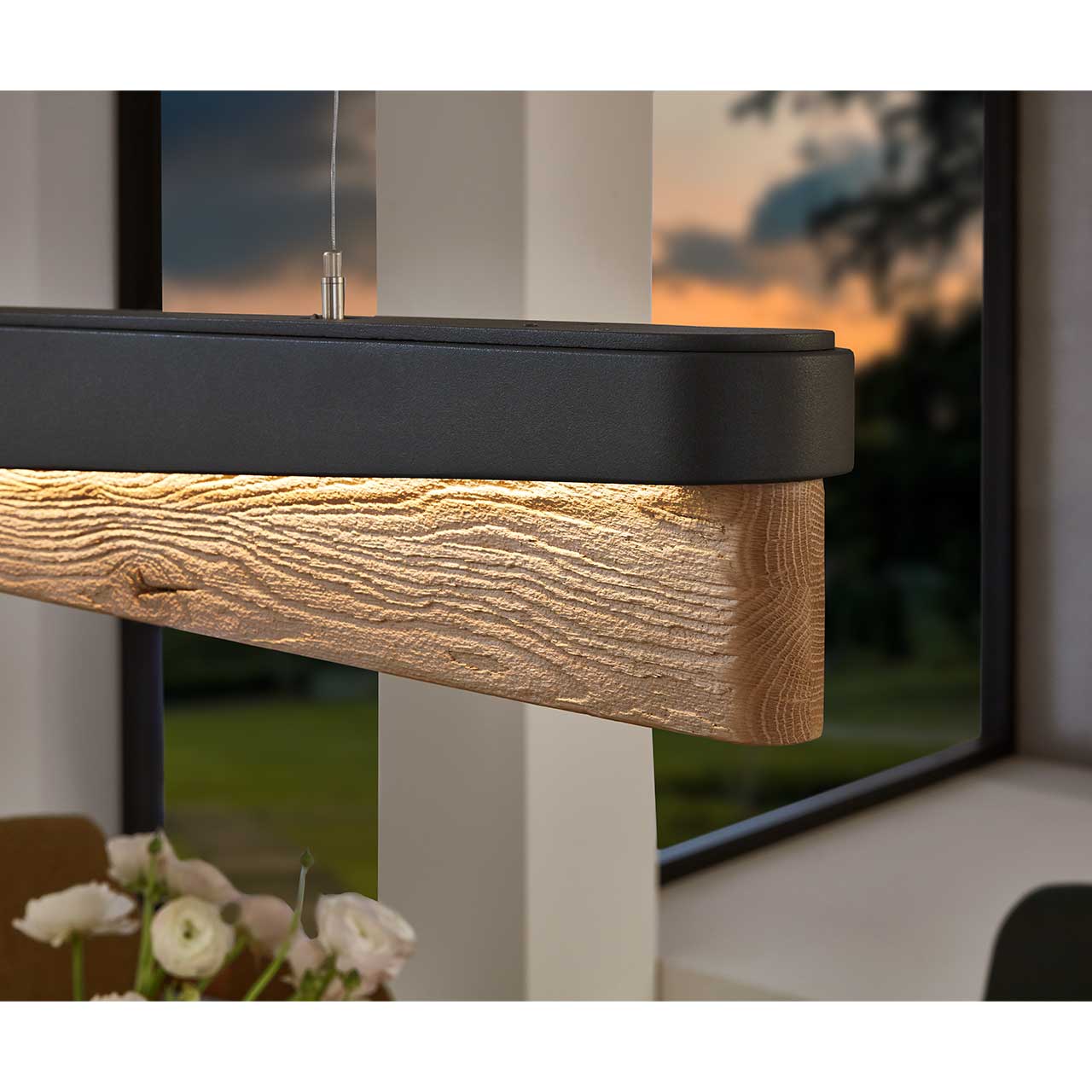 Detailaufnahme einer Paneel-Pendelleuchte aus massivem Holz mit Teileinfassung in Metall Anthrazit. Sichtbar die edle Holzmaserung. 