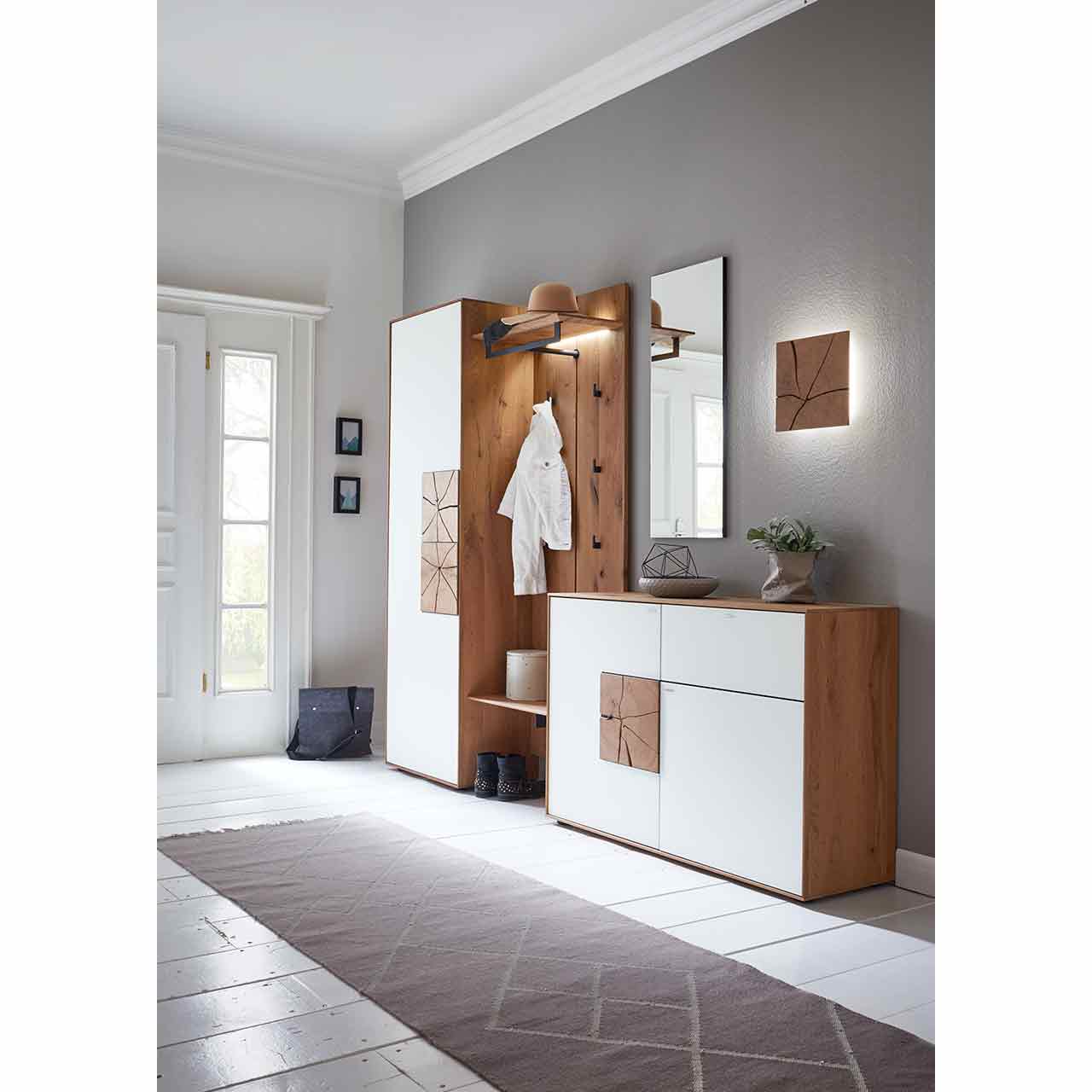 Moderne, fünfteilige Garderobe aus massiver Kerneiche mit beleuchtetem Spiegel und Wandleuchte, Kommode und hohem Stauraumschrank mit weißen Mattglasfronten und Hirnholzkacheln und einem Wandpaneel mit Stange, Ablagen und Haken – vor dunkler Wand