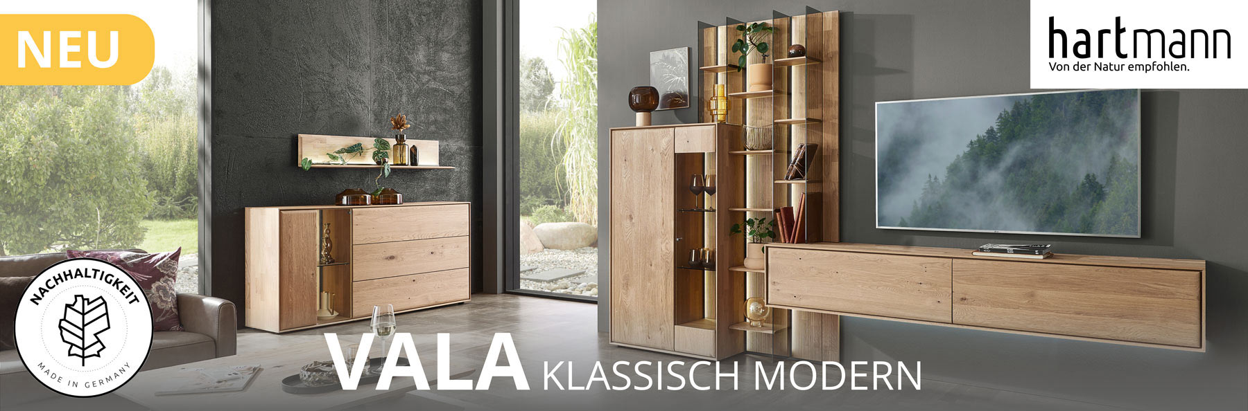 Hartmann Möbel - Möbelserie VALA - Kerneiche Natur - Wohn-/Esszimmermöbel Hartmann VALA - Neue Möbelserie aus Kerneiche Natur kombiniert mit Parsolglas und geschoppten Rückwänden. Ambientebild zeigt schlichtes Lowboard, Wandpaneel mit beleuchteten Glasböden und integriertes Highboard. Weiter links Sideboard darüber Regal.