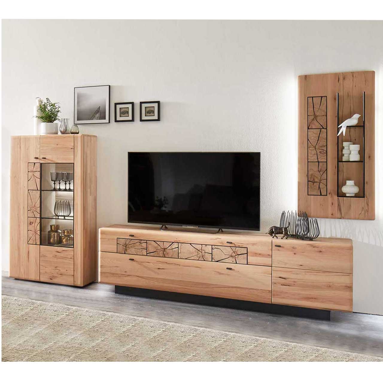 Wohnzimmer mit Wohnwand aus massiver Kernbuche. Links ein Highboard mit zwei Türen, eine Holz eine Glastür. Rechts daneben ein Lowboard mit dunklem Sockel. Weiter rechts an der Wand ein hängendes Paneel mit Hirnholzscheiben und drei Glasböden.