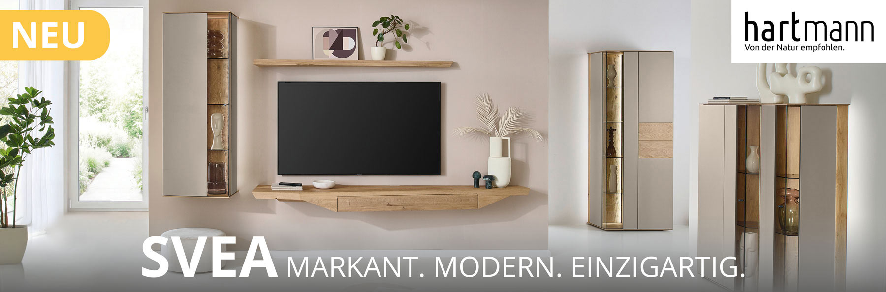 Hartmann Möbel - Möbelserie SVEA - Wohn-/Esszimmermöbel - Kerneiche Natur und Lack Sand Hartmann SVEA - Massivholzmöbel aus Kerneiche Natur kombiniert mit Lack Sand und Riffholz. Ambientebild zeigt asymmetrisches Hängelowboard, Hängevitrine und Wandboard. Davor passendes Highboard mit Glastüren, dahinter Standvitrine.