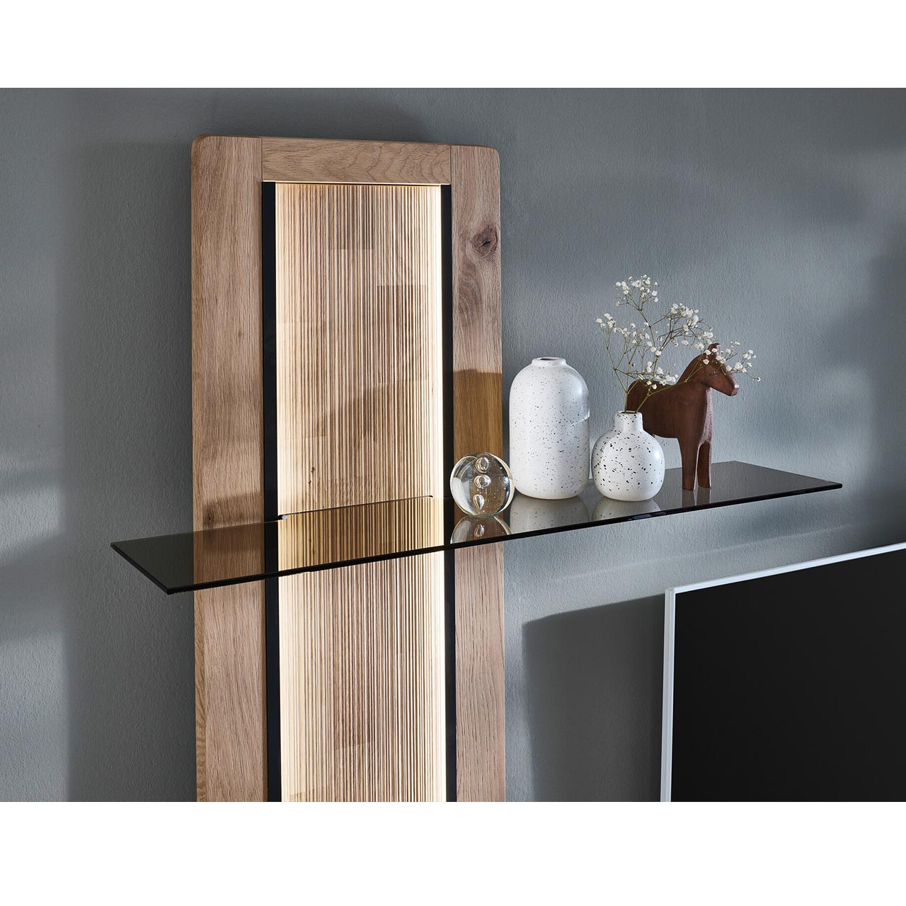 Detailansicht des VIDA Wandpaneels mit Beleuchtung der geschroppten Rückwand sowie des oberen Glasbodens aus edlem Parsolglas.