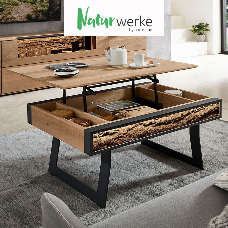 Hartmann NATURWERKE - individuelle und funktionelle Couchtische aus Massivholz kombiniert mit Glas und Metall. Ambientebild zeigt rechteckigen Couchtisch aus Kerneiche Natur auf zwei Metallkufen mit hochgeklappter Tischplatte darunter Stauraumfach.