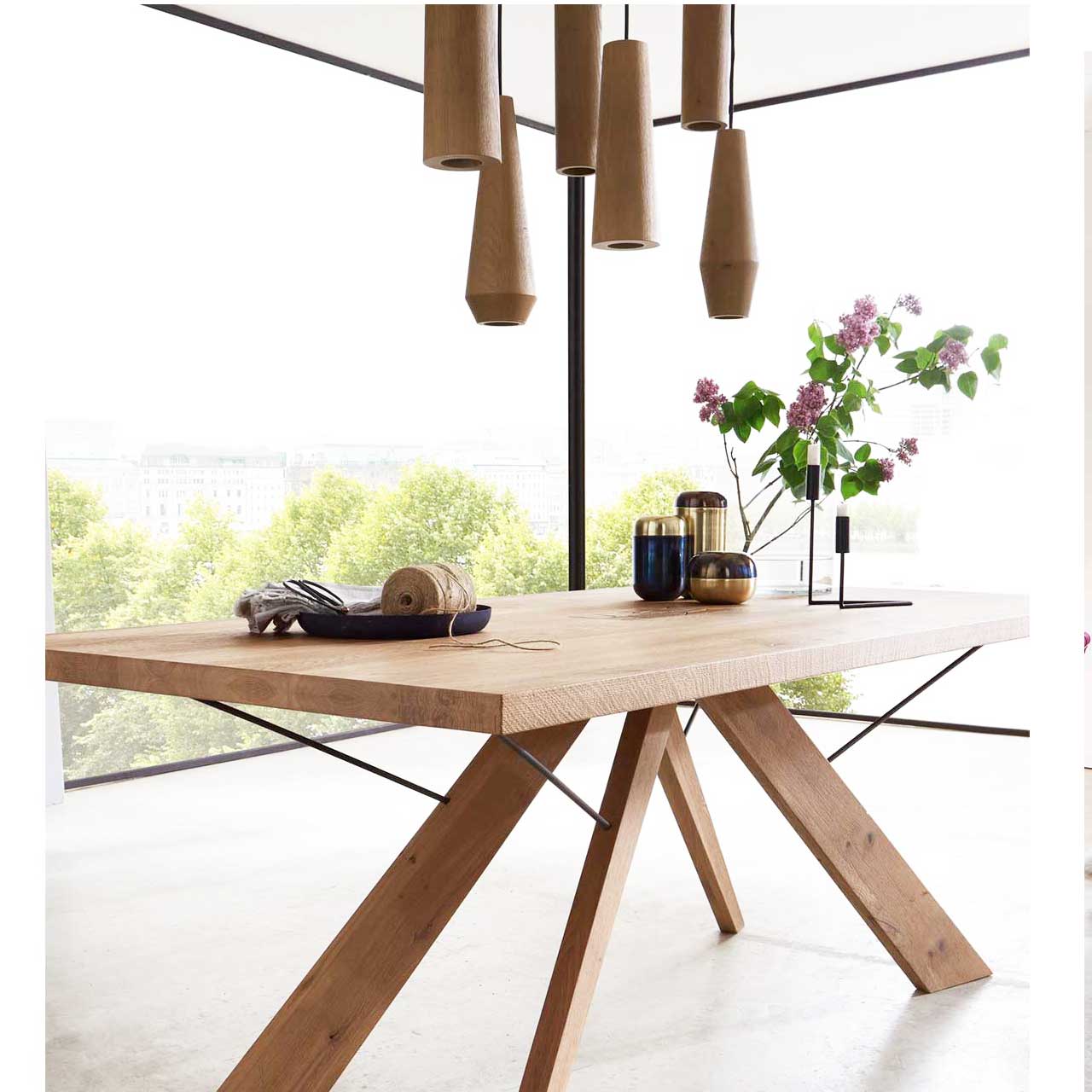Modernes Esszimmer mit rechteckigem Holztisch. Darüber hängend eine Pendelleuchte mit sechs unterschiedlichen, zylinderförmigen Holzkörpern aus massiver Kerneiche 