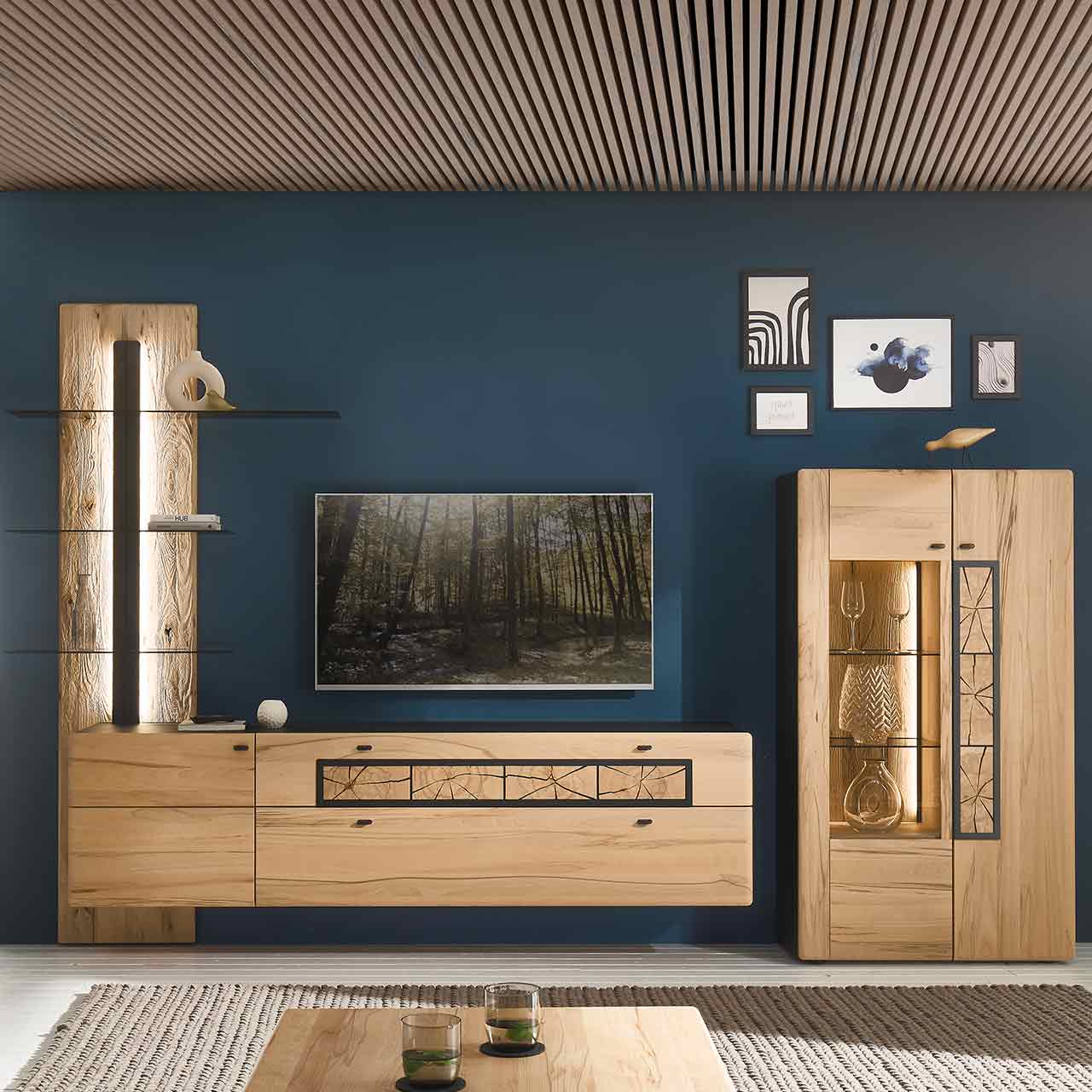 Wohnzimmer mit Wohnwand aus Kernbuche: Wandpaneel mit Glasböden, Hängelowboard mit Holztür und Schubkästen. Daneben Highboard mit Glas- und Holztür, verziert mit Hirnholzscheiben.
