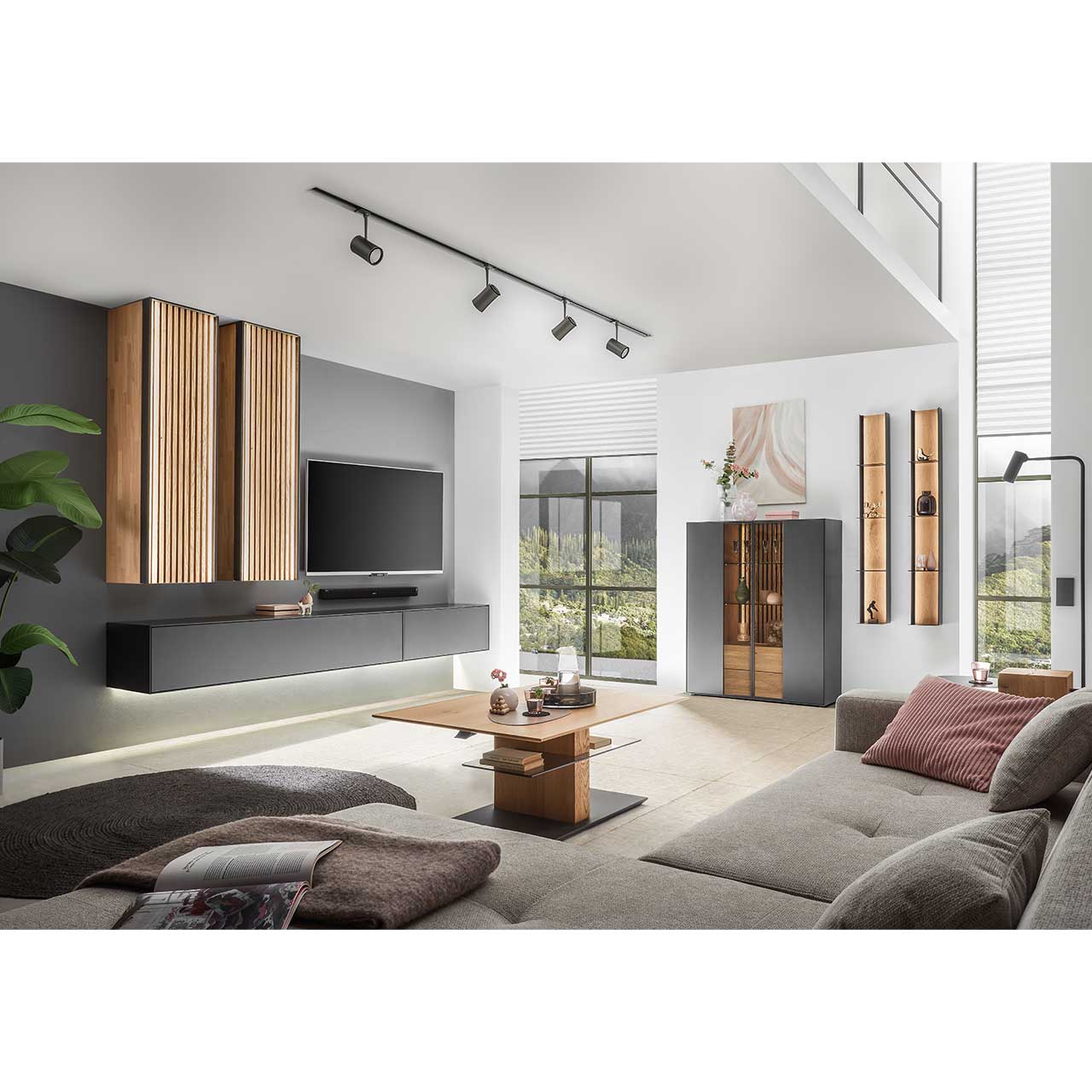 Modernes Wohnzimmer mit Wohnwand aus massivem Holz anthrazit lackiert und hellen Holzlamellen. Rechts an der Wand das passende Highboard und zwei Wandregale. Im Vordergrund der dazugehörige Couchtisch.