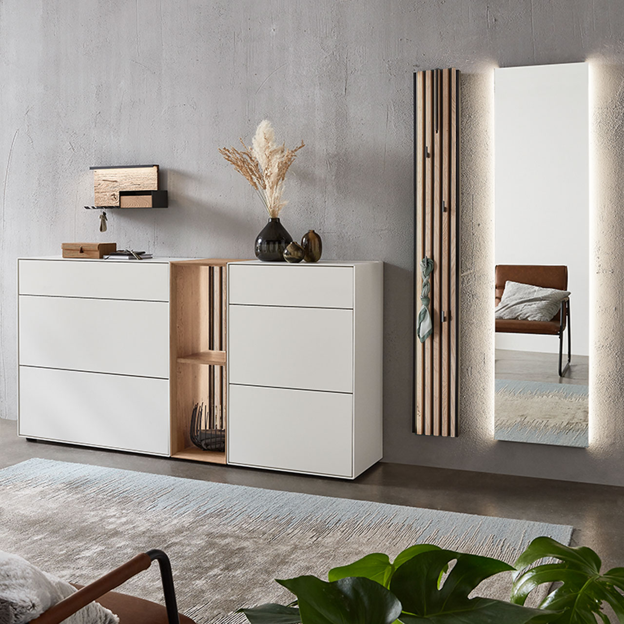 Moderne fünfteilige Garderobe aus massiver Kernbirke und Kerneiche Natur: Regalelement mit Lamellen-Rückwand zwischen zwei weiß lackierten Stauraumschränken, dazu ein Garderobenpaneel mit Lamellen-Akzent und ein rechteckiger Spiegel.