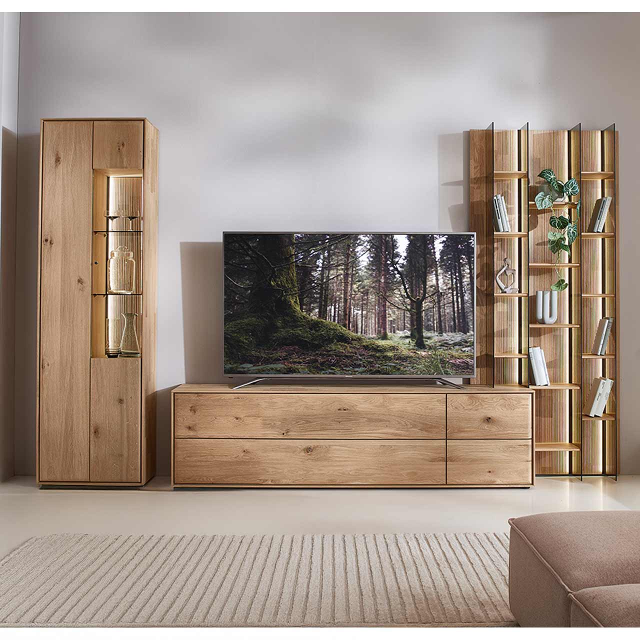 Moderne dreiteilige Wohnwand aus massiver Kerneiche Natur bestehend aus einer Standvitrine,  einem hohen Wandregal mit Holzböden, beleuchteten Glasseiten und geschroppter Rückwand und einem darin integriertem Lowboard.