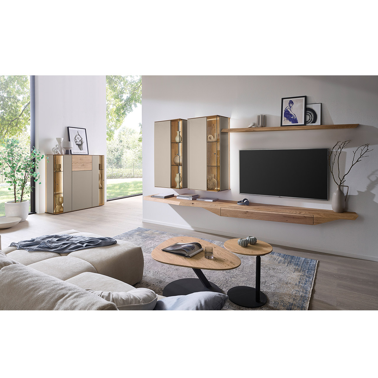 Wohnzimmer mit moderner Massivholzwohnwand bestehend aus Hängelowboard, Hängevitrinen, sowie Wandboard - im asymmetrischen Design. Links passendes Highboard mit Glastüren, davor zwei Beistelltische aus Holz